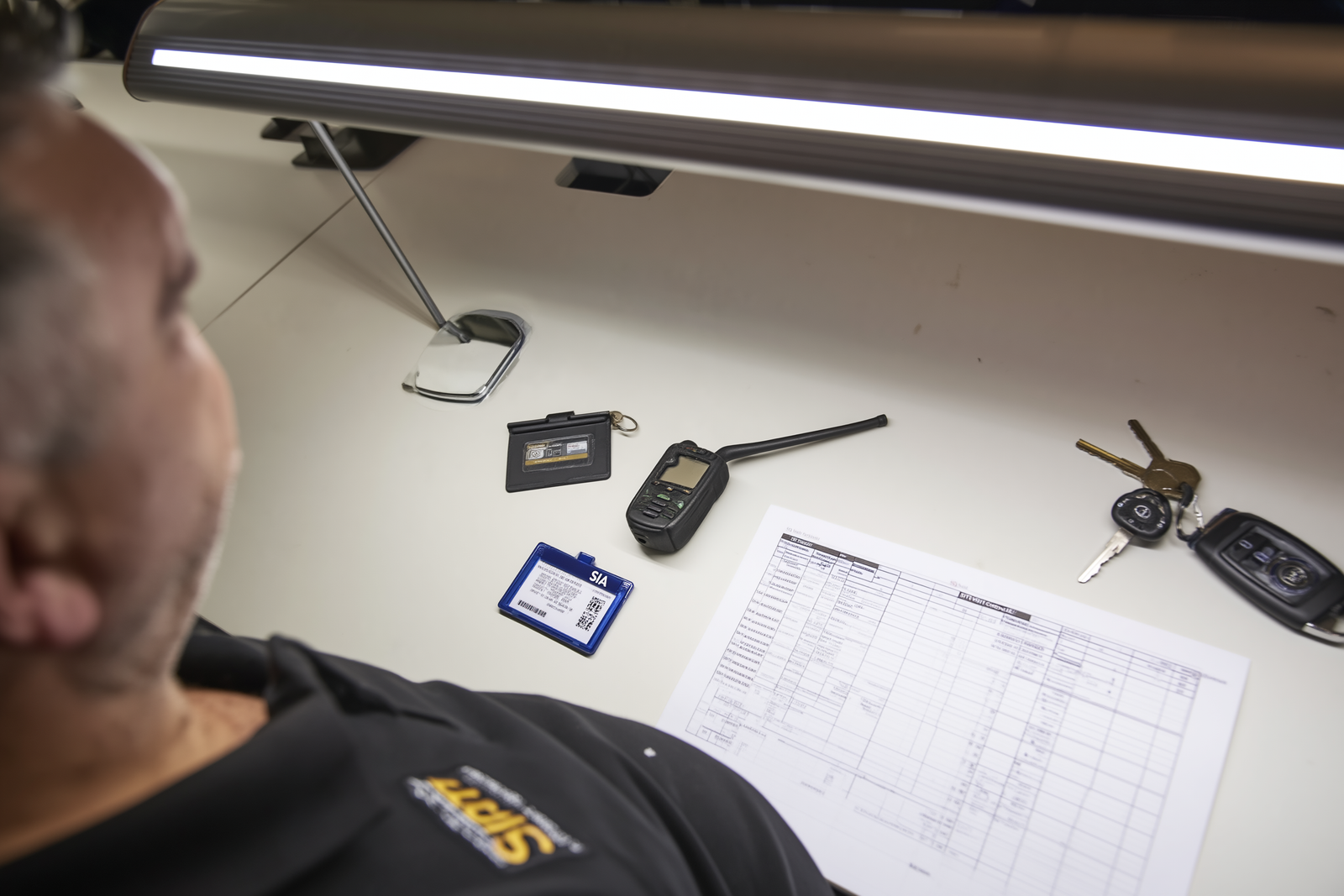 Security operations desk with access control key card, radio, and monitoring equipment